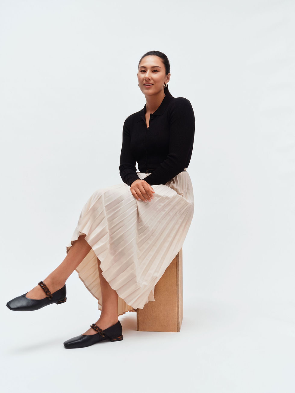 Woman sitting on a box with legs and arms crossed