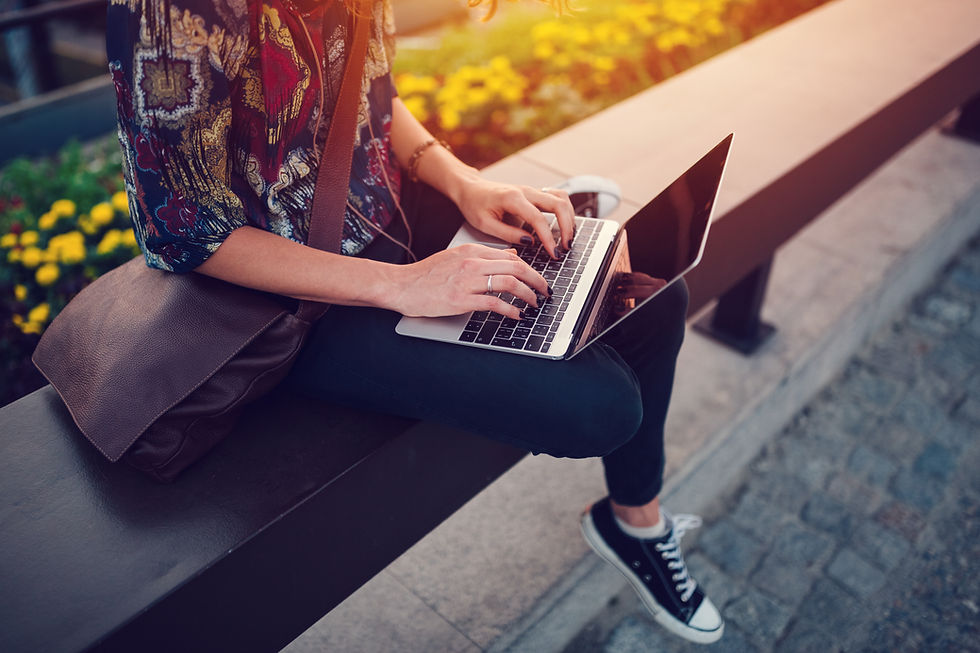A woman on her laptop with a field of sunflowers behind her