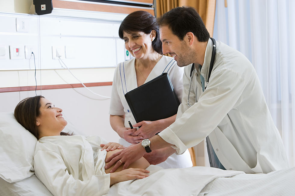A pregnant woman sits in a hospital being cared for by a medical professional