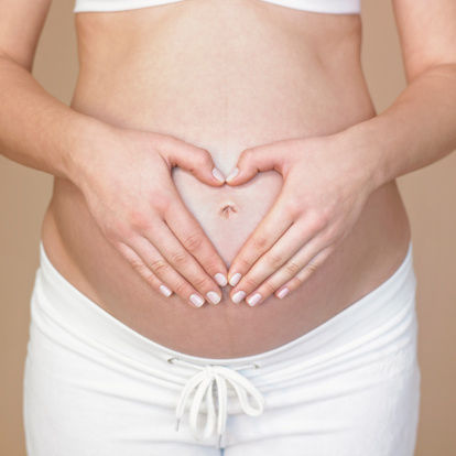 A pregnant woman holds her hands on her pregnant belly